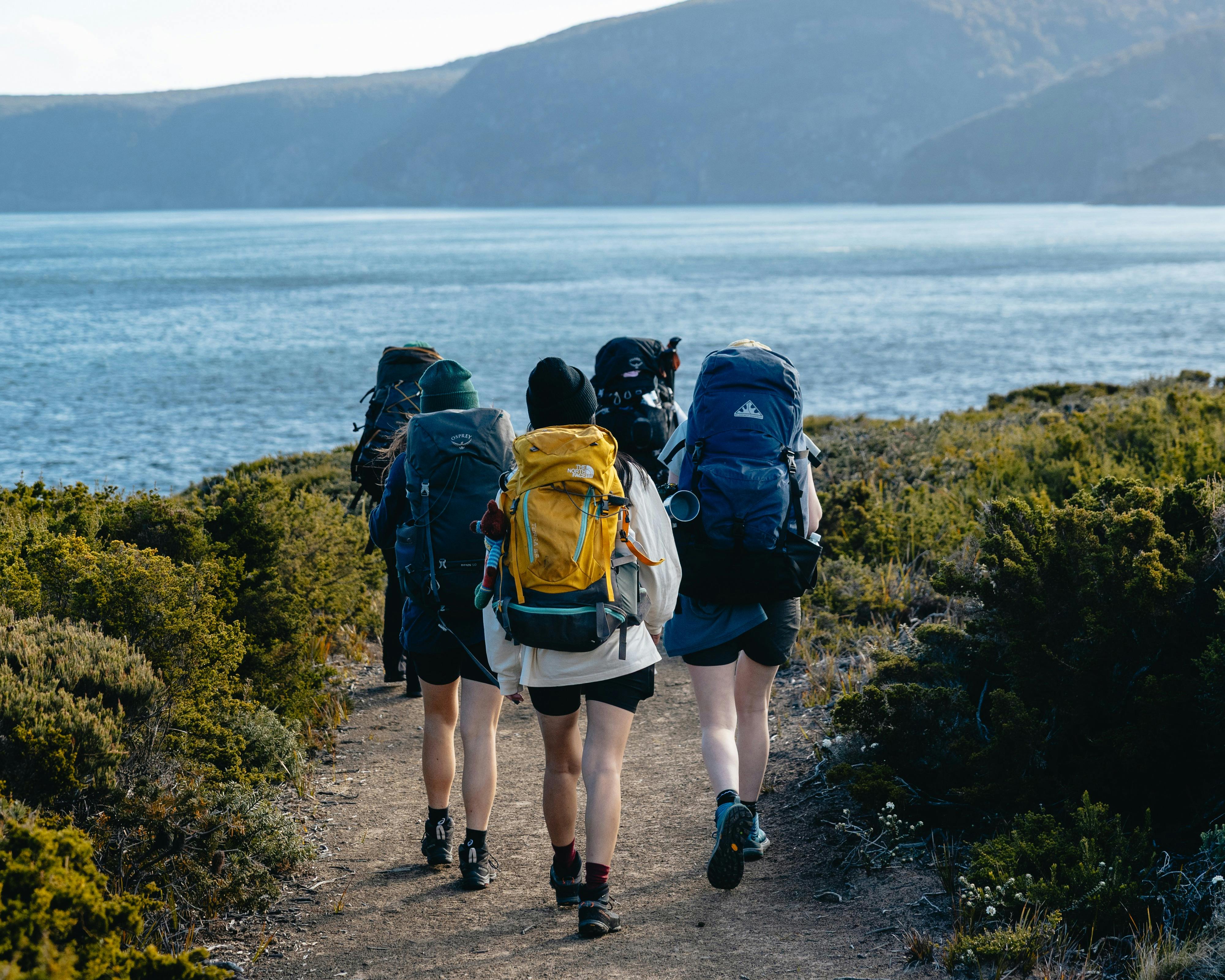 Group of women with packs on their pack walking to find camp at dusk
