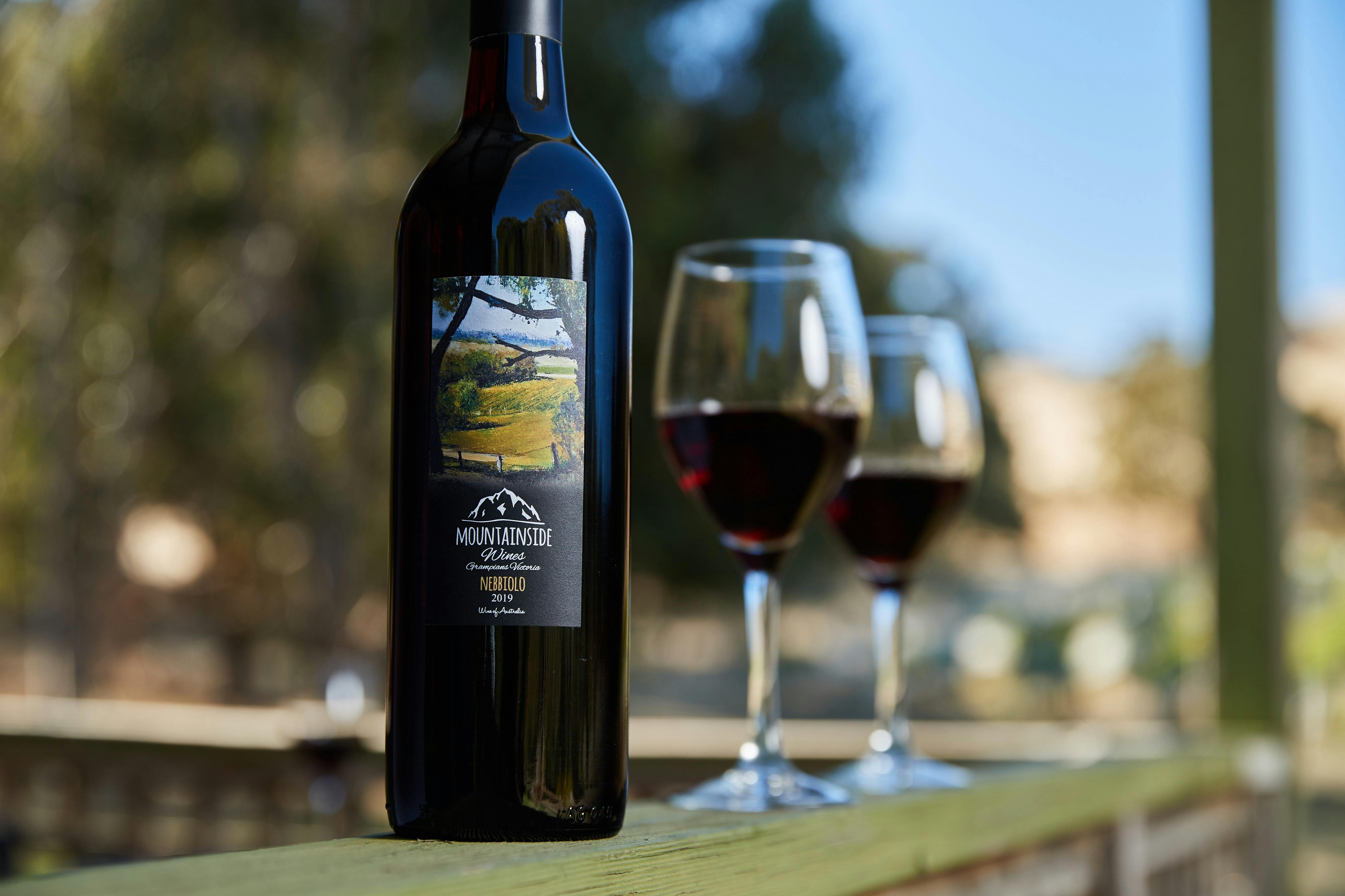 A Bottle of Nebbiolo with two glasses standing on the railing
