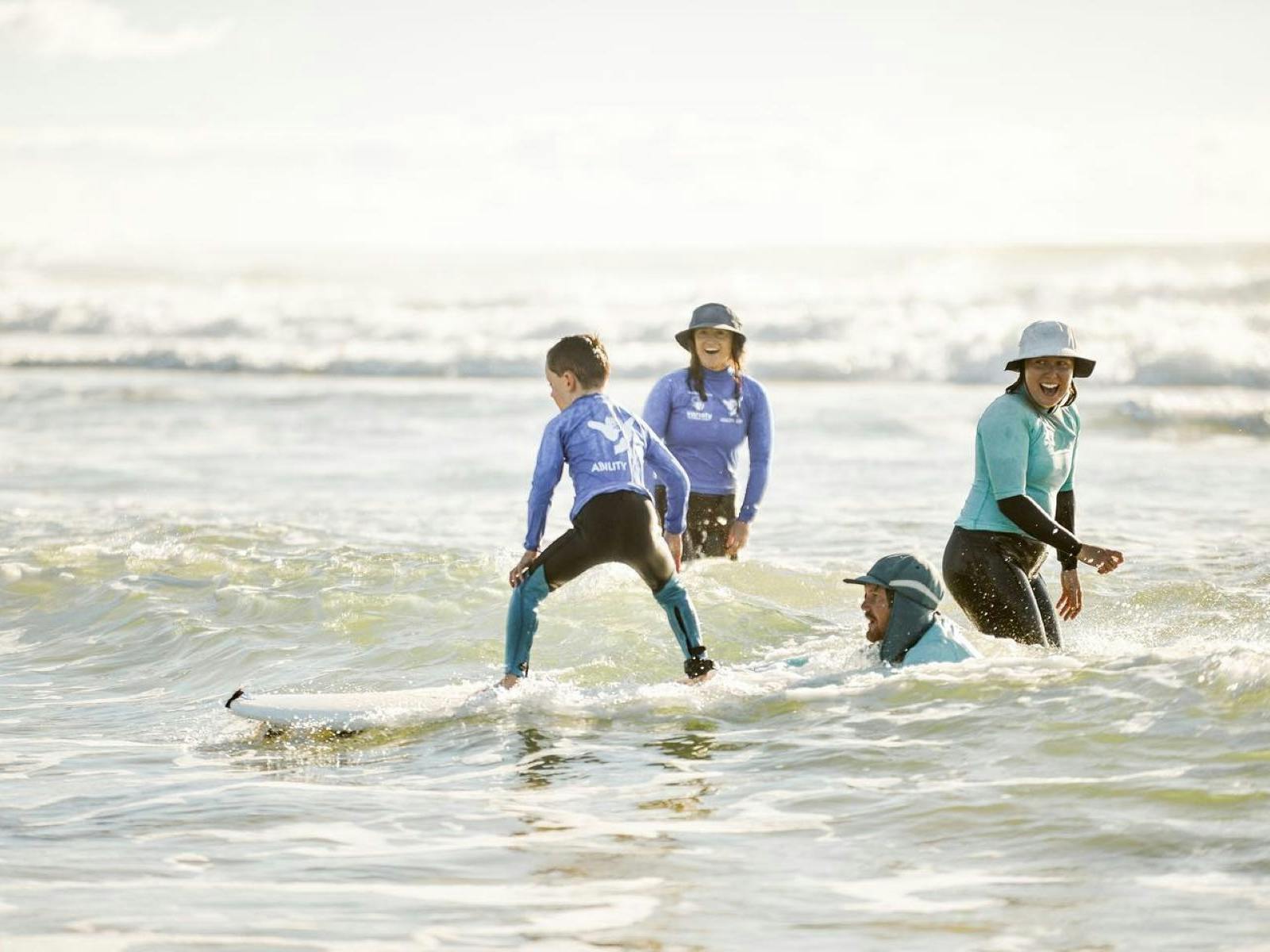 Kid surfing with instructors grinning