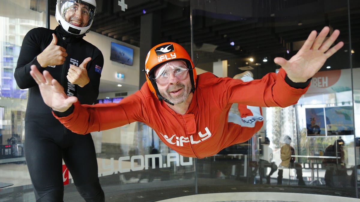 Intstructor gives a thumbs up to the camera while male in an orange suit flies solo.
