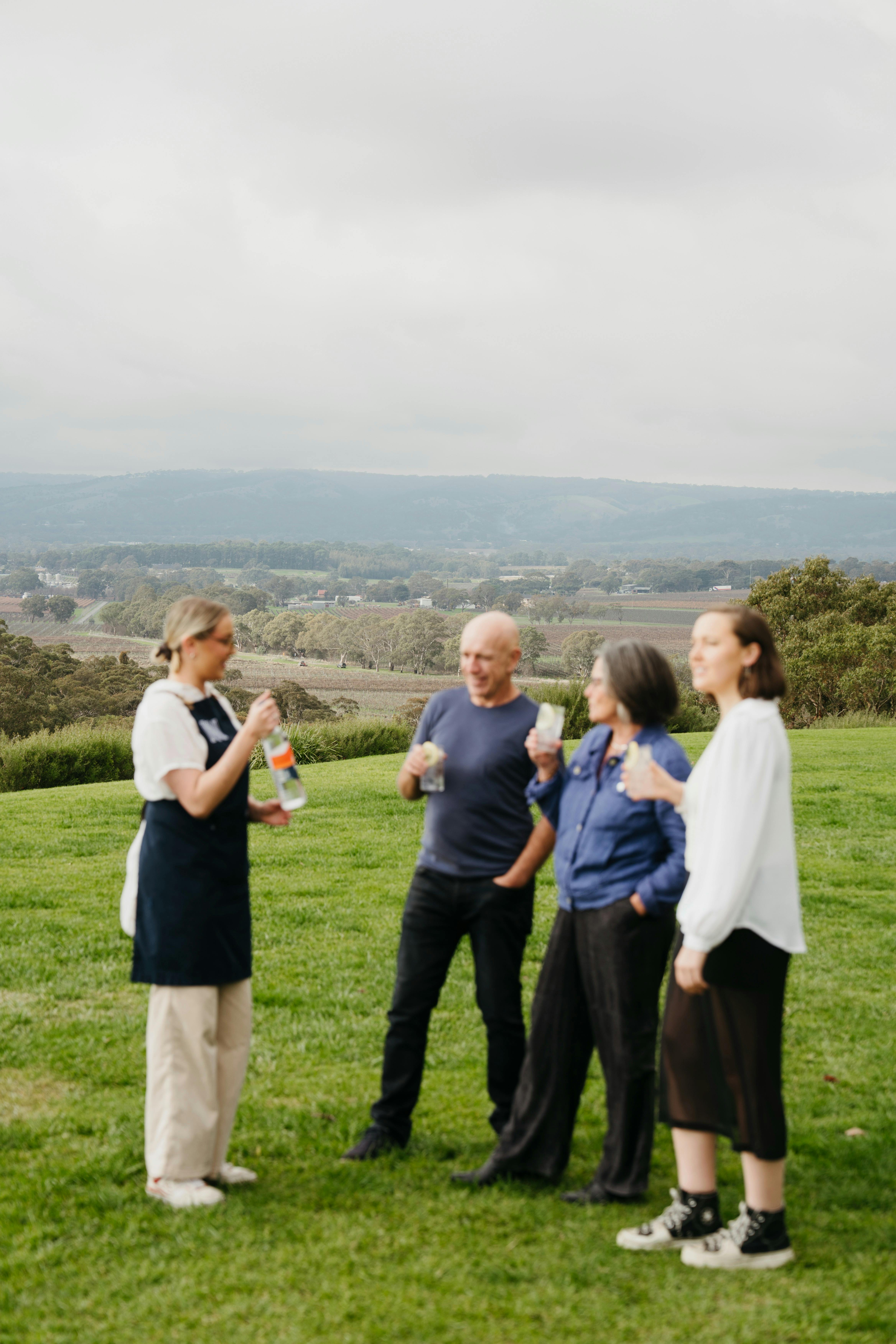 gin expert and guests standing infront of rolling hills and vineyard of mclaren vale