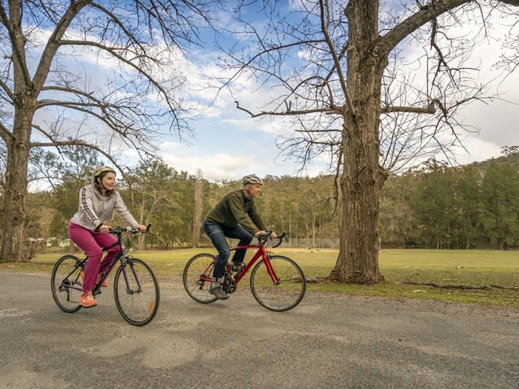 A man and a woman enjoy a bike ride near Wombeyan picnic area. Photo: John Spencer &copy; DCCEEW