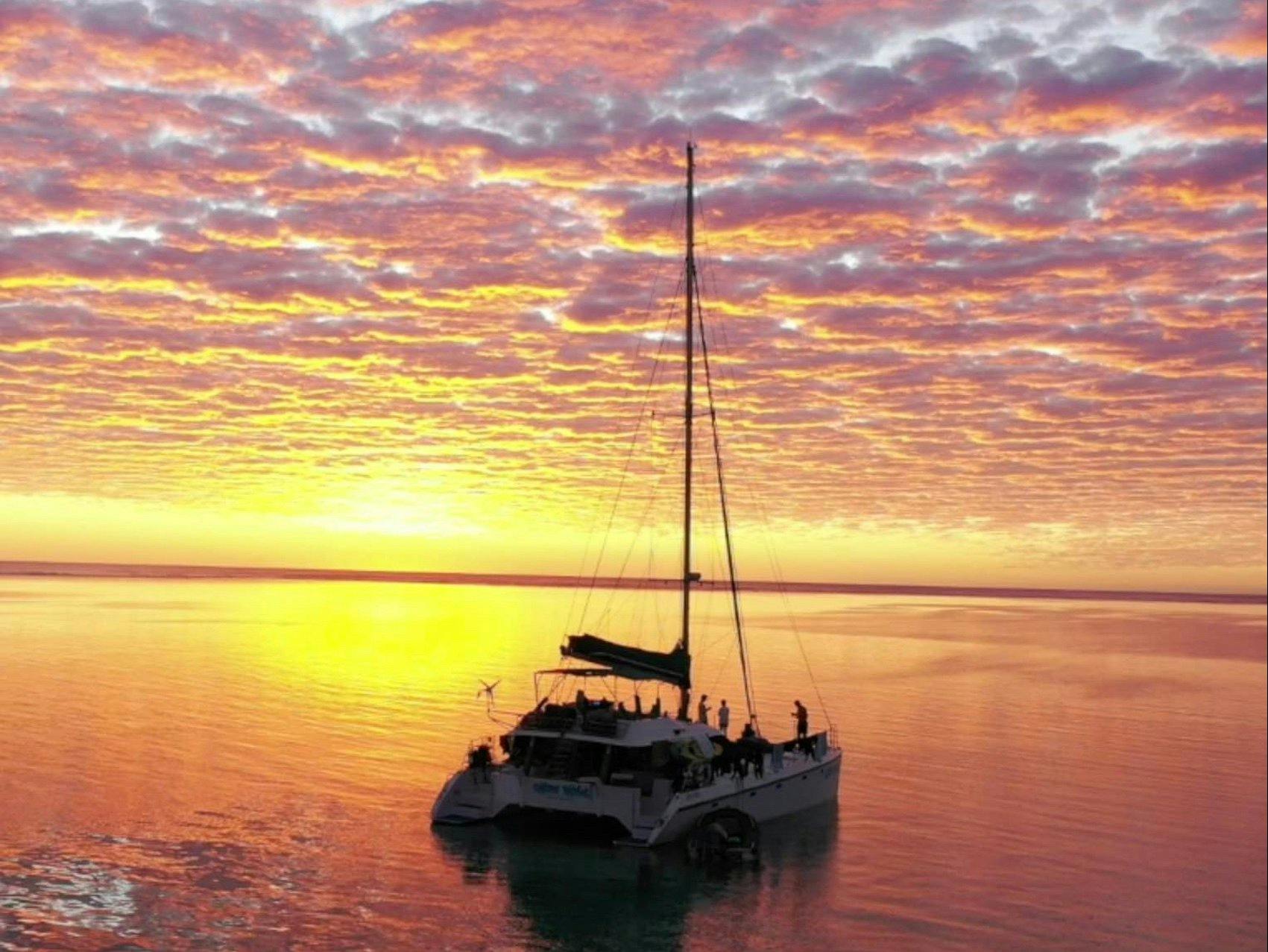 The sun setting over the Indian Ocean with sailing vessel Shore Thing in the foreground.