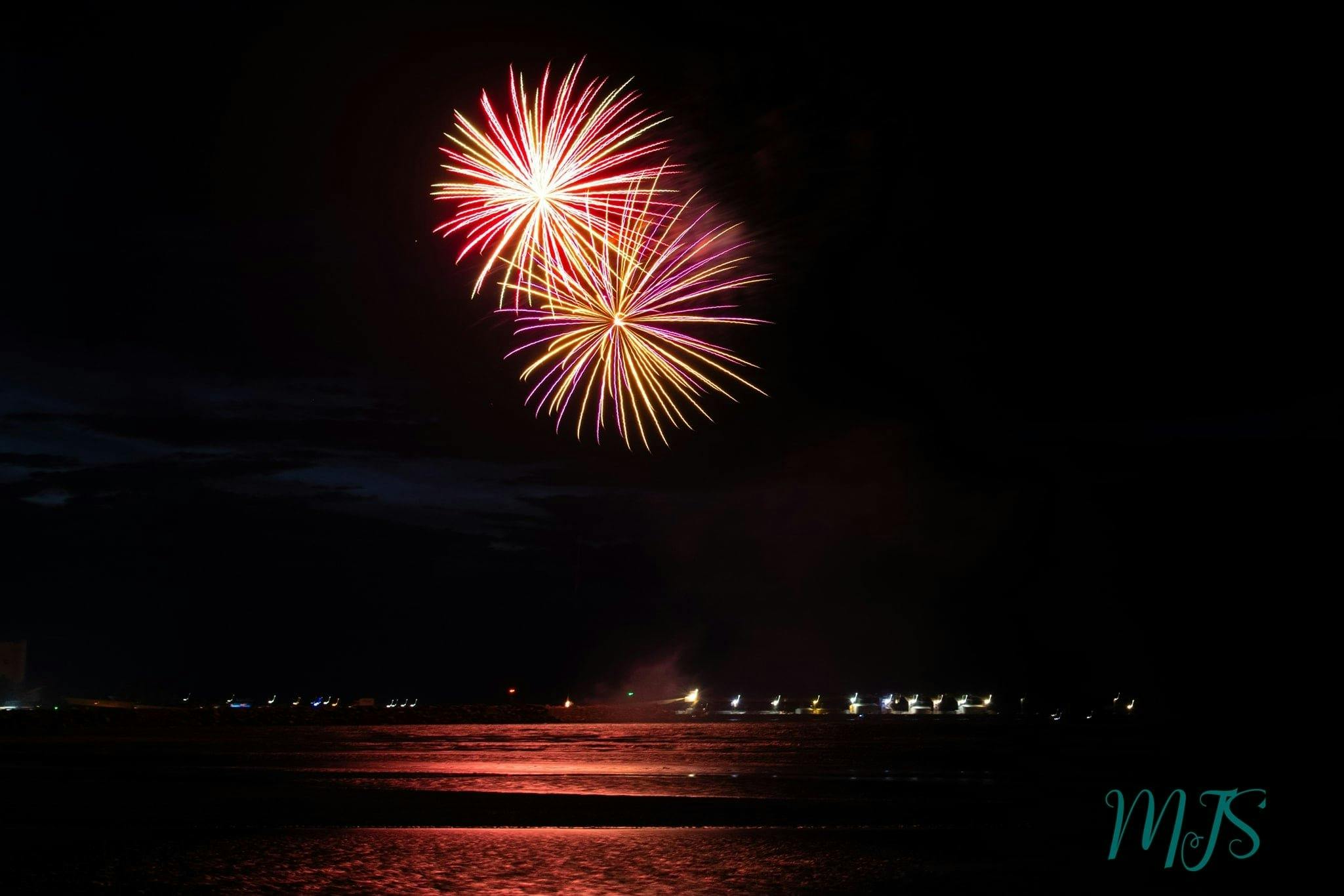 Golden, and purple firewroks over the ocean at night