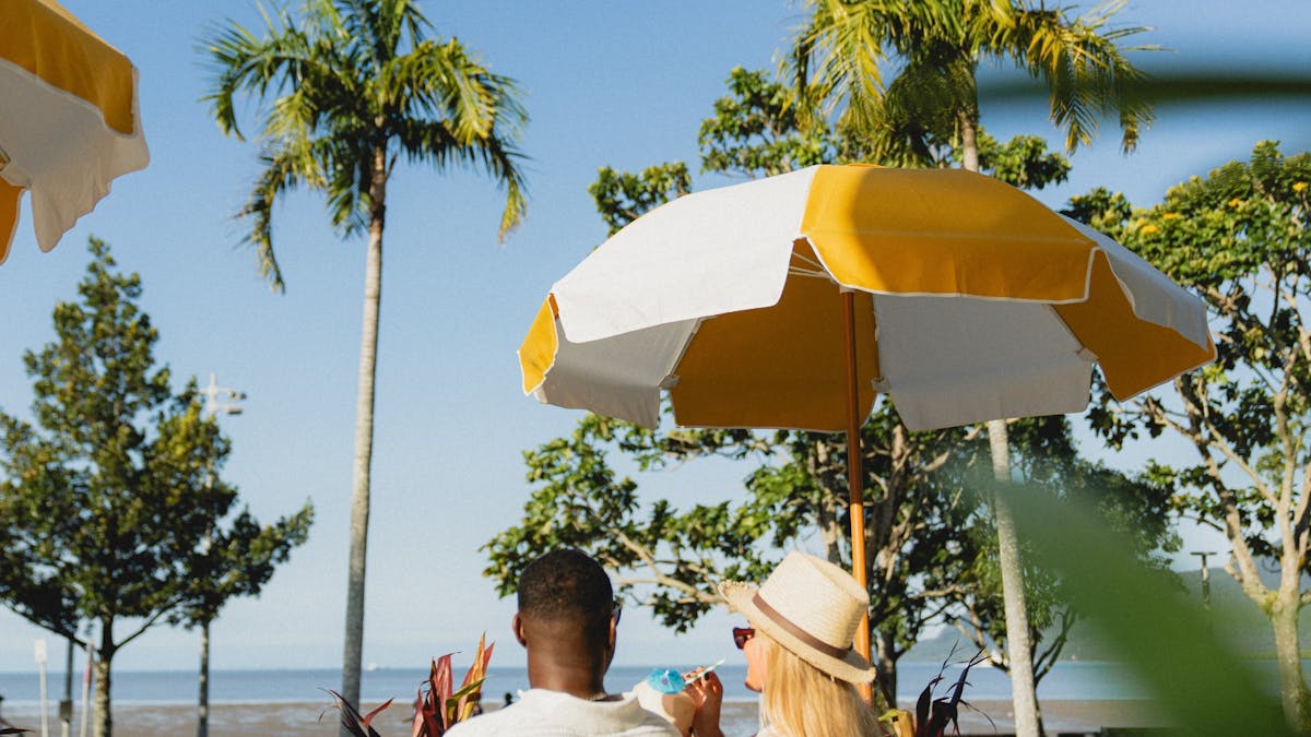 A couple sitting on a sun lounge looking over the esplanade view with cocktails in their hands