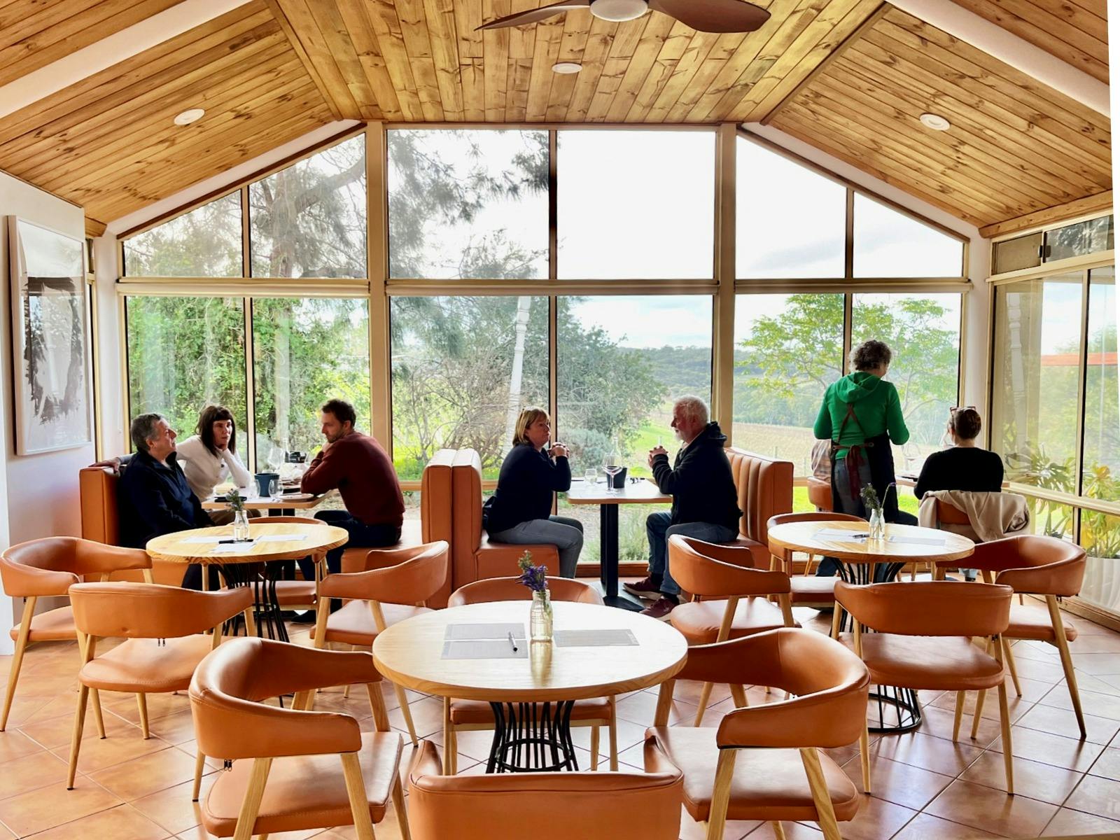 Interior photo of Aphelion Cellar Door showing booth and table seating, people and picture windows