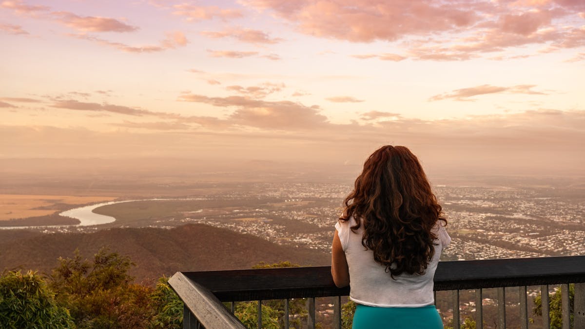 The back of a woman leaning on a railing staying out to the city of Rockhampton.