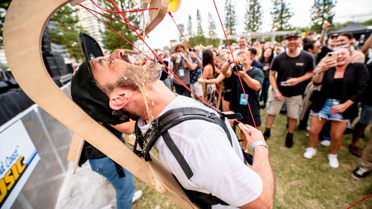 Man drinks a beer from a puppet machine strapped to him