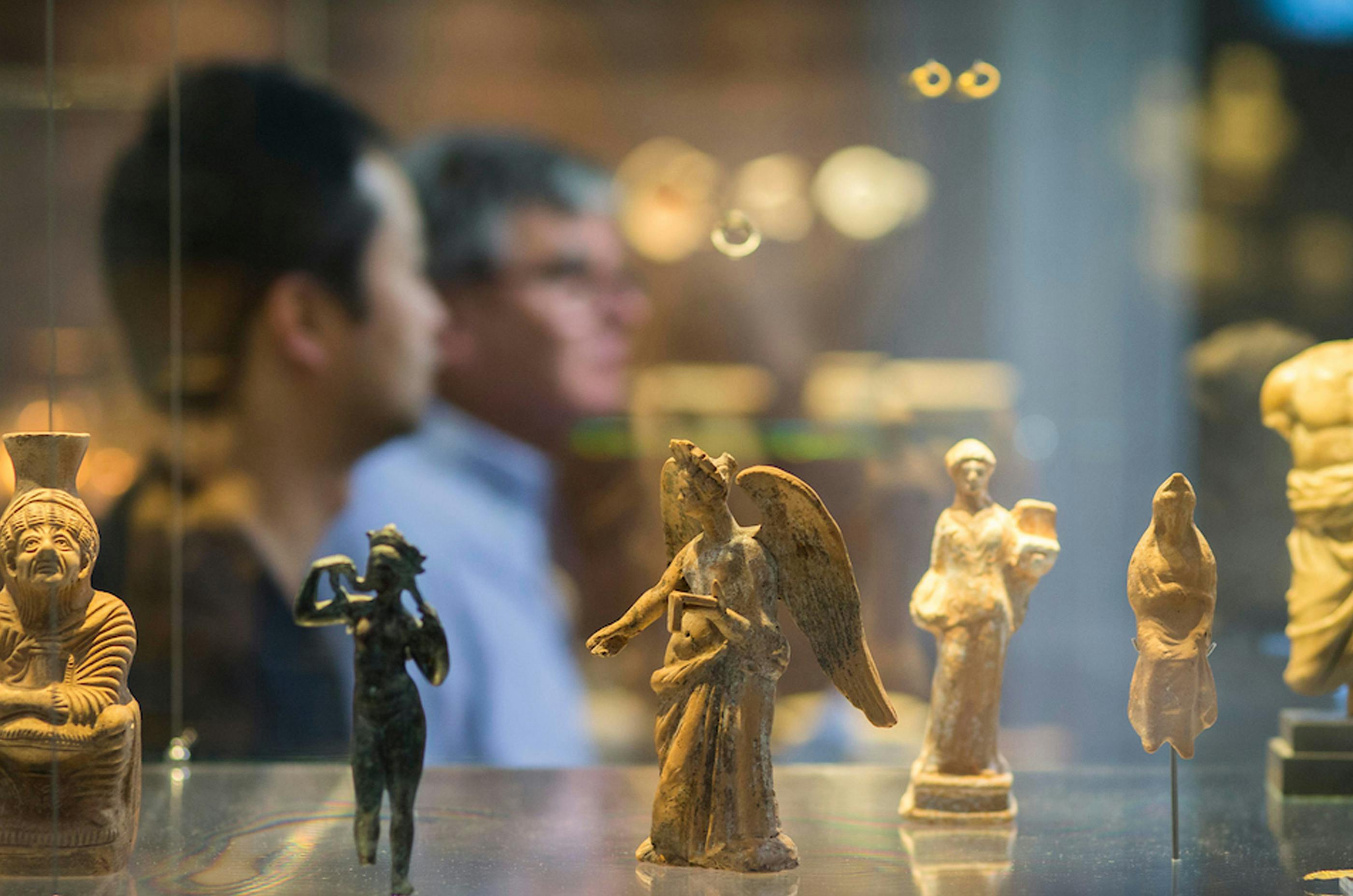 People viewing tiny statues on display in the museum