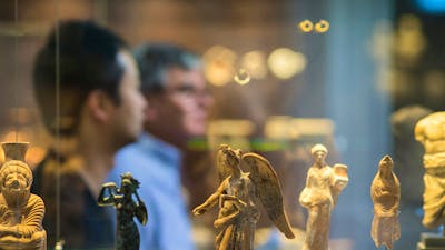 People viewing tiny statues on display in the museum