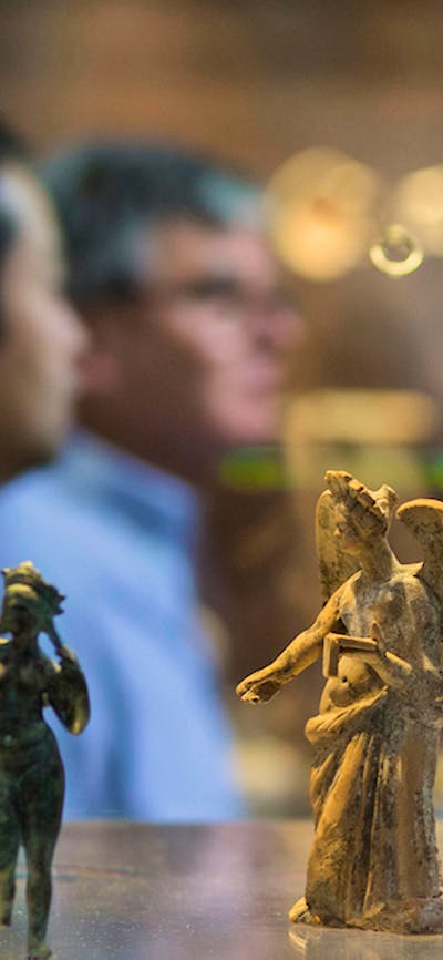 People viewing tiny statues on display in the museum