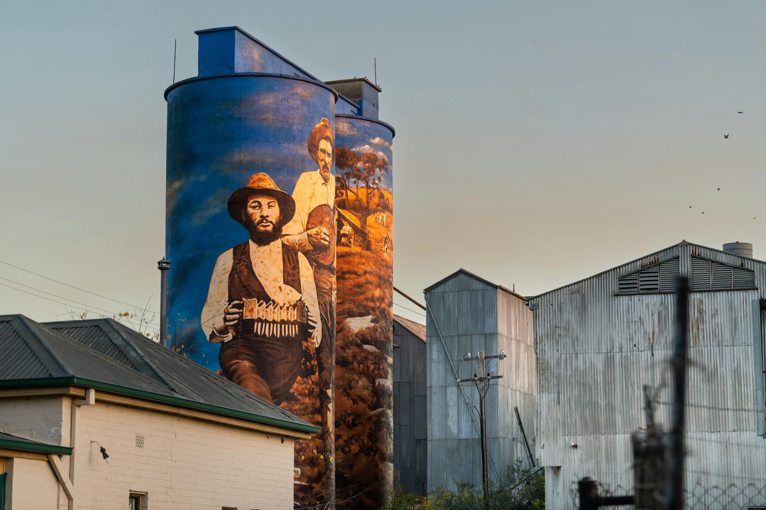 Alt aerial shot of newer painted side of the silo arts depicting two men with instruments.