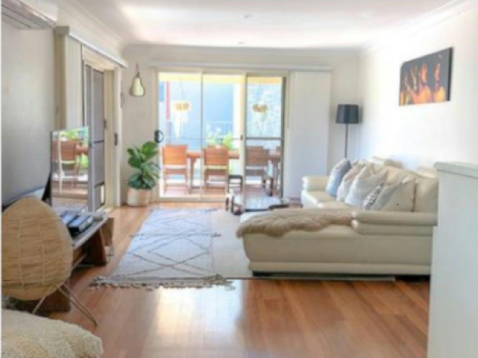 Light filled lounge room with comfy couch and timber floors