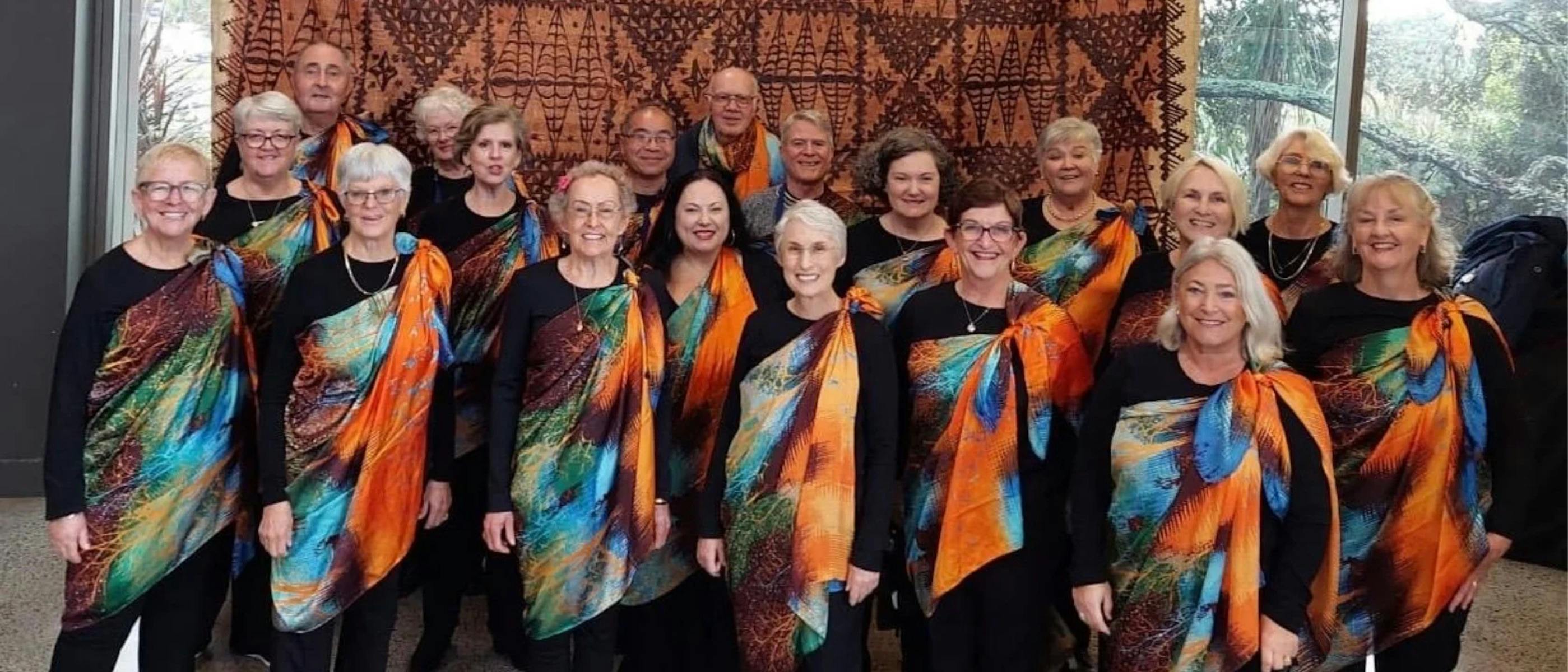 A group of singers wearing colourful scarves stand together smiling