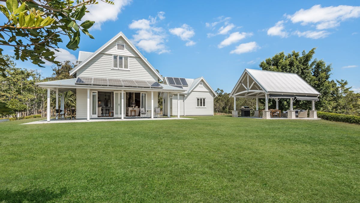View from expansive lawns to Cascade Cottage timber house, pergola & garage - 2/3 bed  off-grid