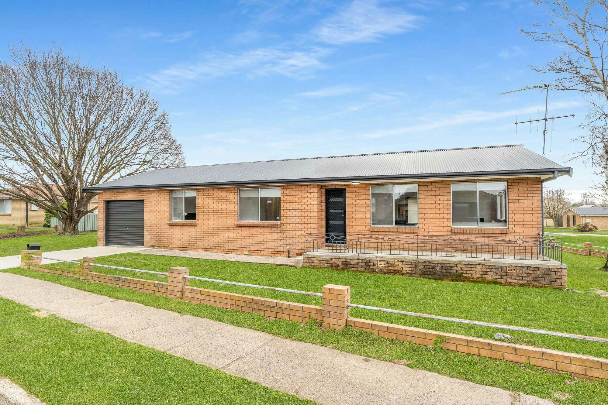 Brick house with large yard and lots of windows, and driveway