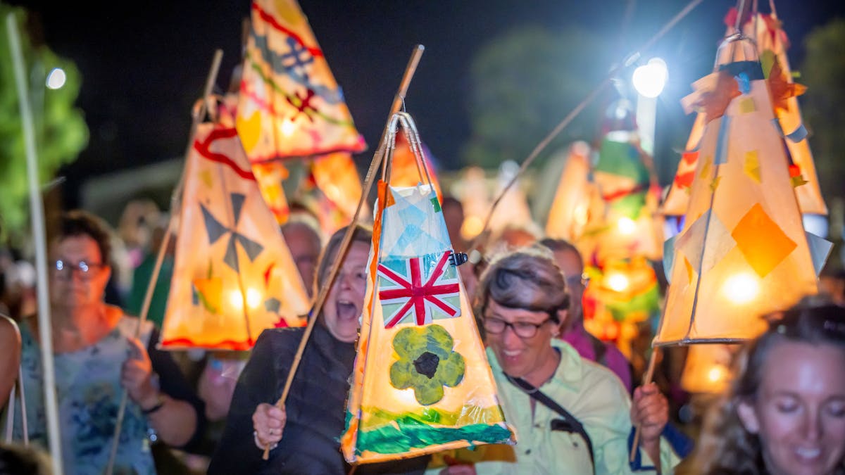 Women walking at night in a group carrying paper lanterns that are lit up. Women walking at night in a group carrying paper lanterns that are lit up.