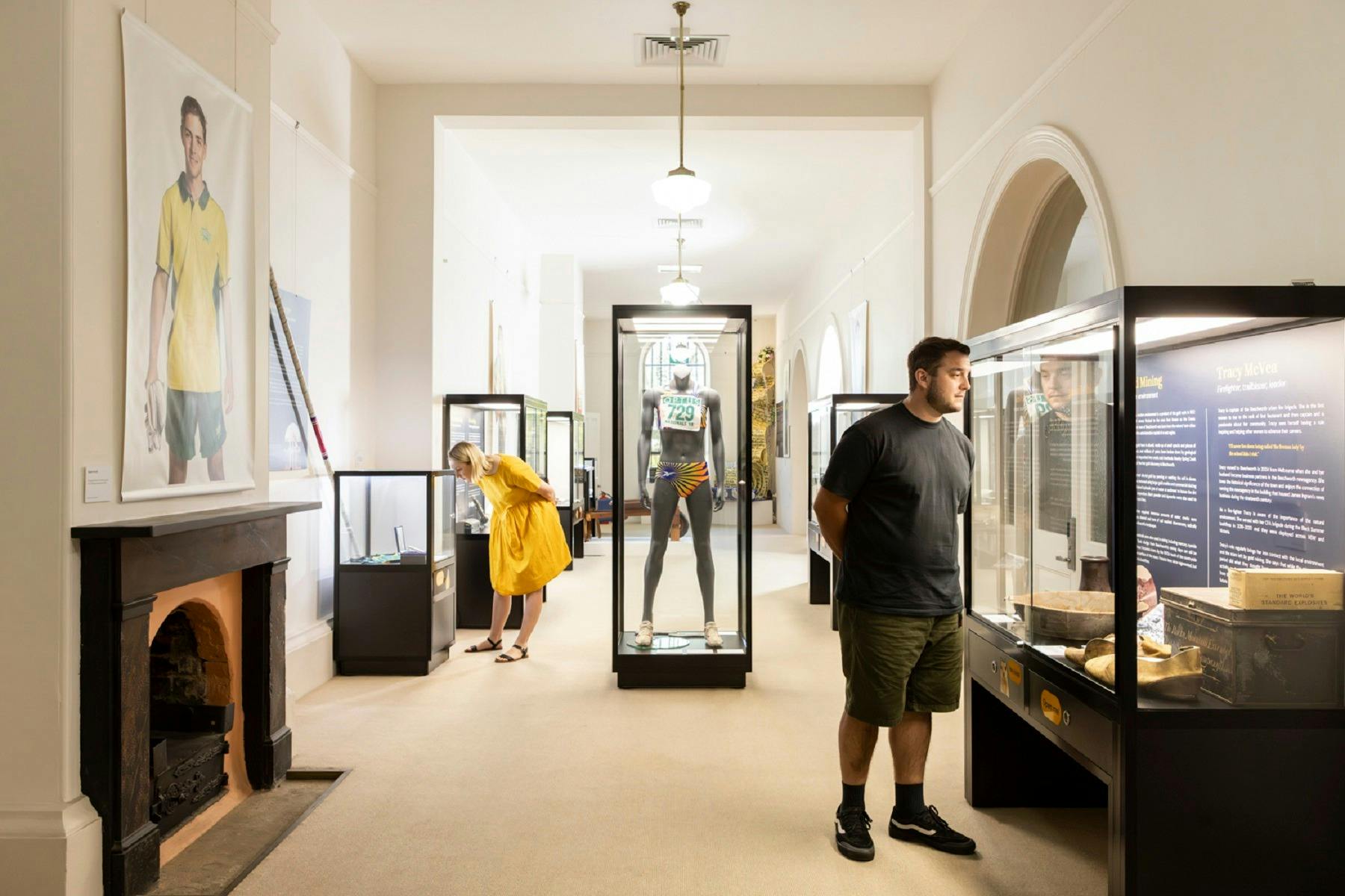 a long hall exhibition with large portrait photos on the walls. Glass display cabinets throughout