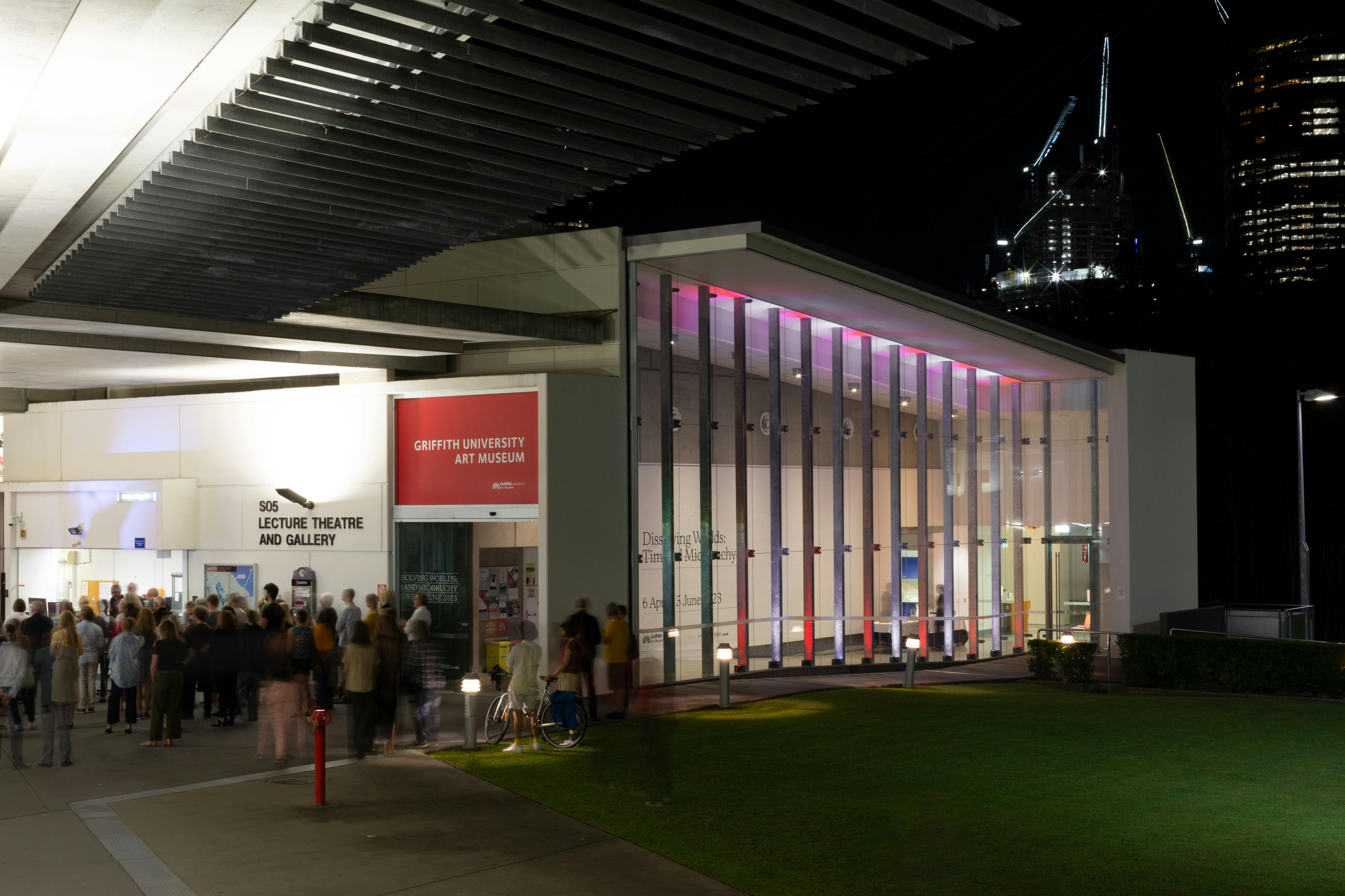 Griffith University Art Museum from the exterior at night. A large crowd is infront of the gallery.