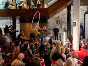 An acrobat is negotiating a path through the young audience