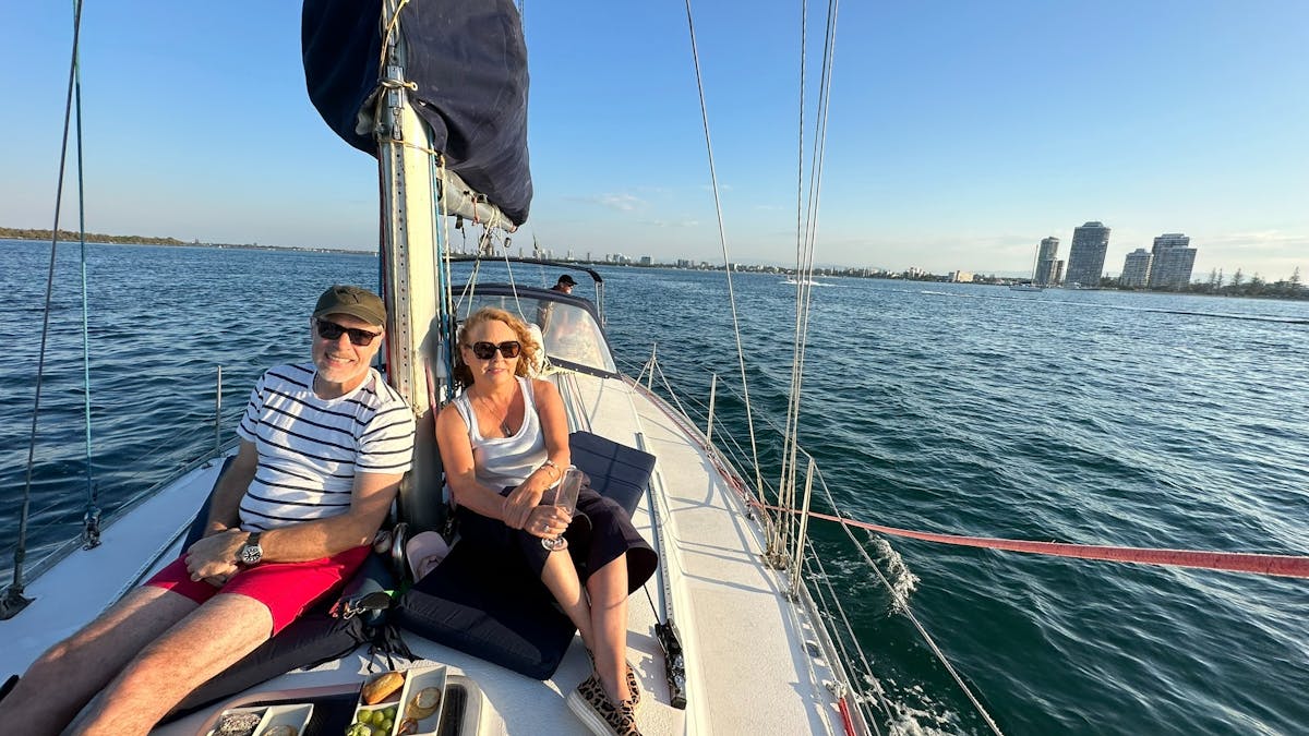 Couple sitting on deck of Epsilon, 38ft monohull yacht. Enjoying an afternoon sail.