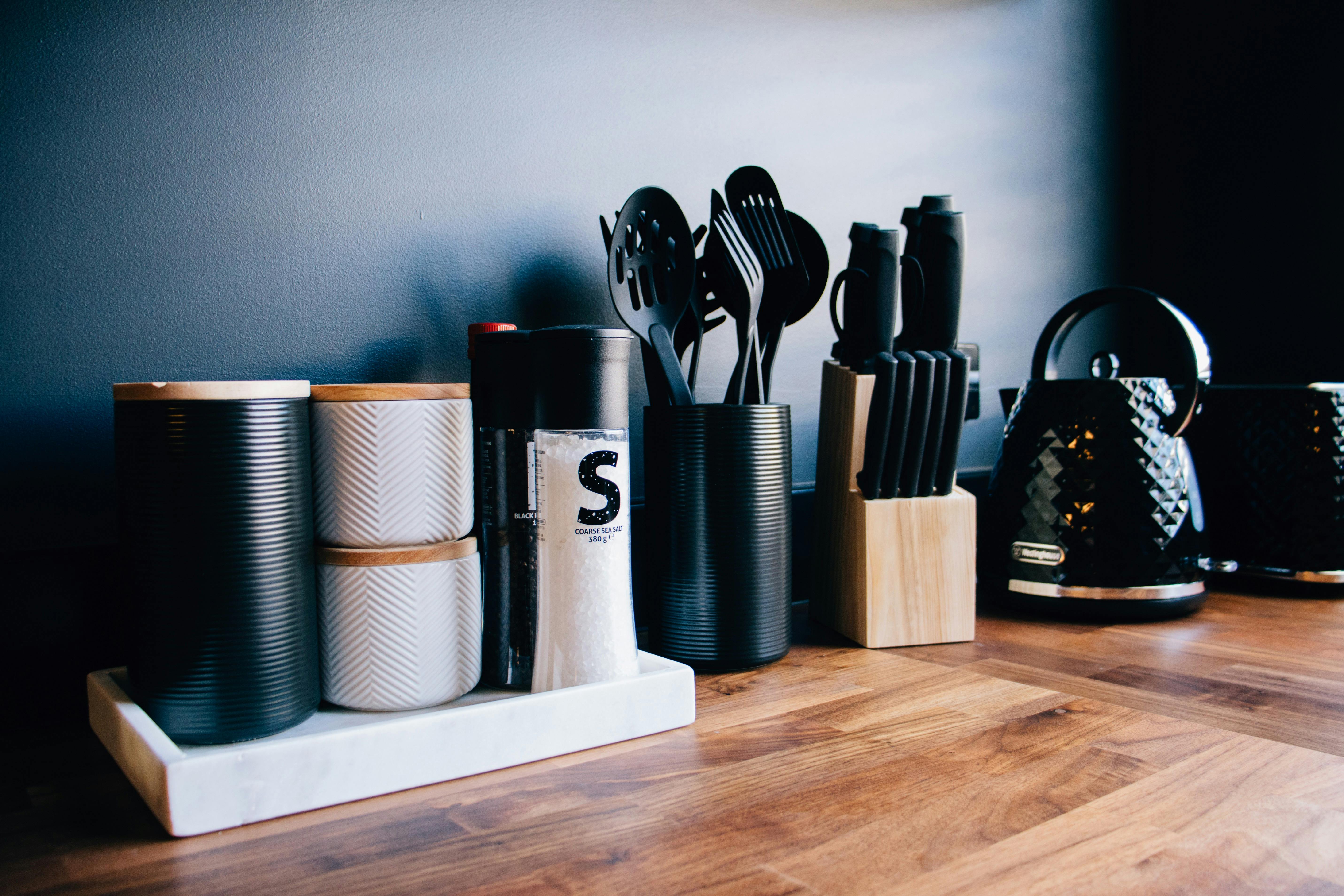Black and white kitchen utensils on a wooden bench.