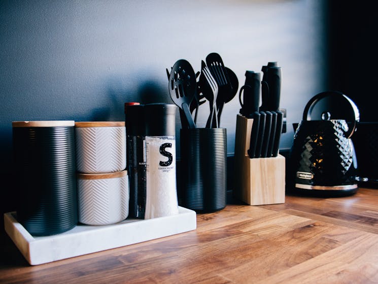 Black and white kitchen utensils on a wooden bench.