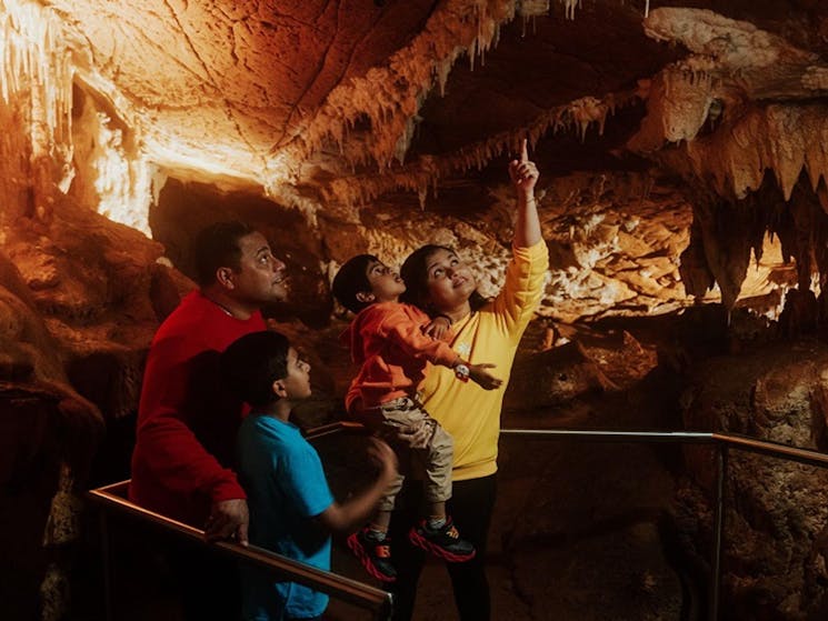 A woman points out a cave detail to her family during a guided tour of Mulwaree Cave, part of