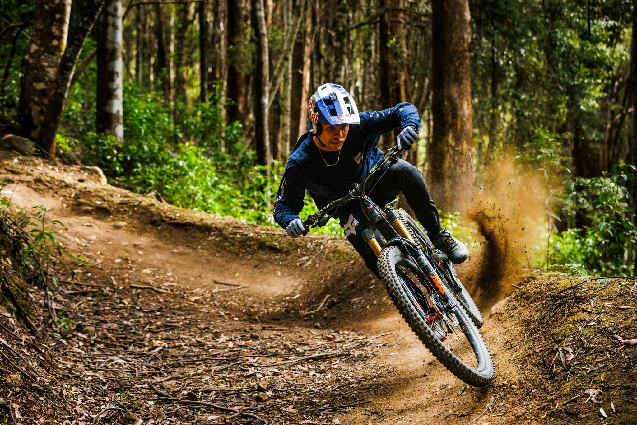 Off road cyclist taking a sharp corner and kicking up dust at maydena bike park
