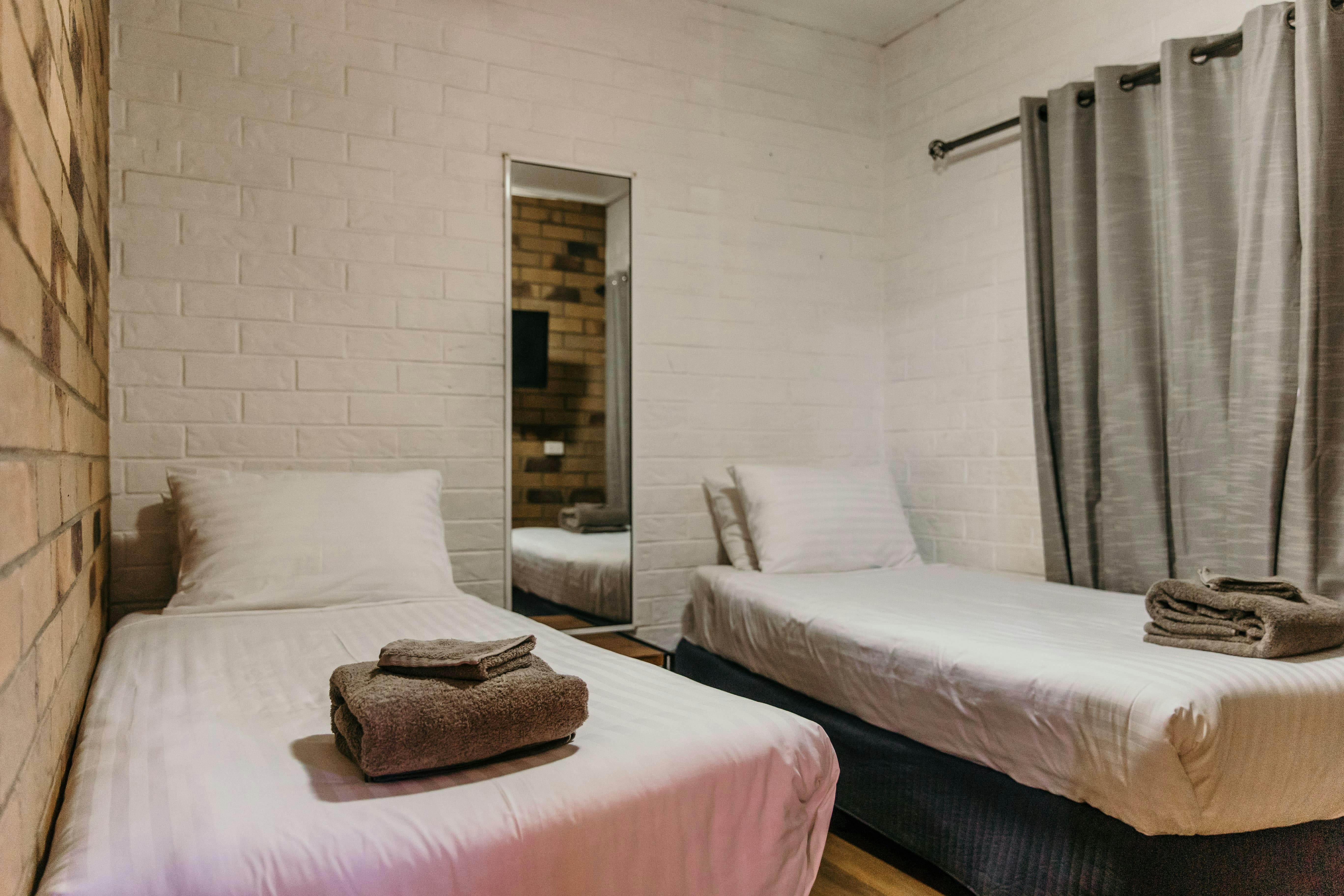 2 single beds with towels on the end of each one.