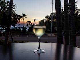 a wine glass with the sunset in the background overlooking the esplanade