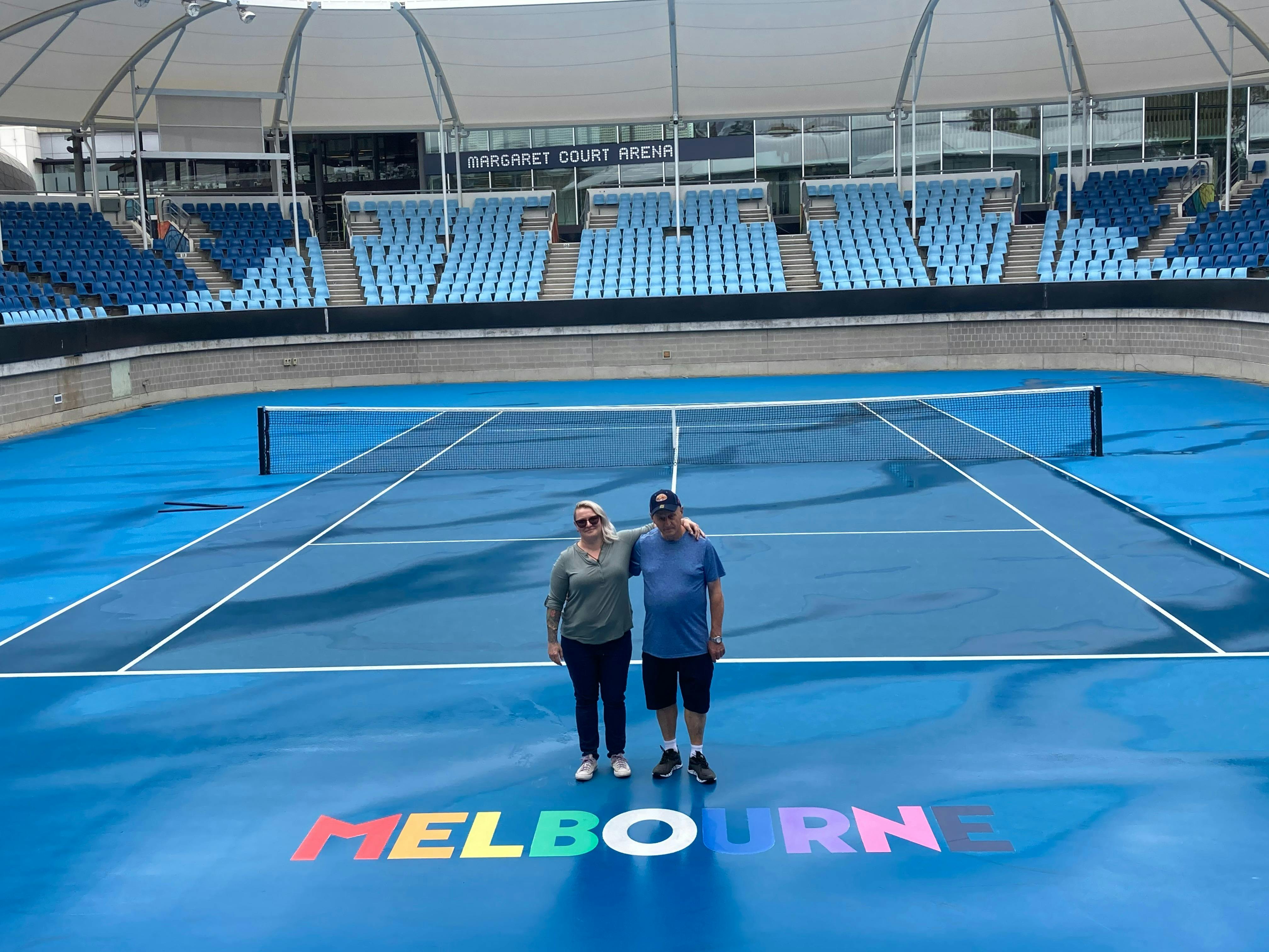 Man and woman standing on blue tennis court with Melbourne printed on it