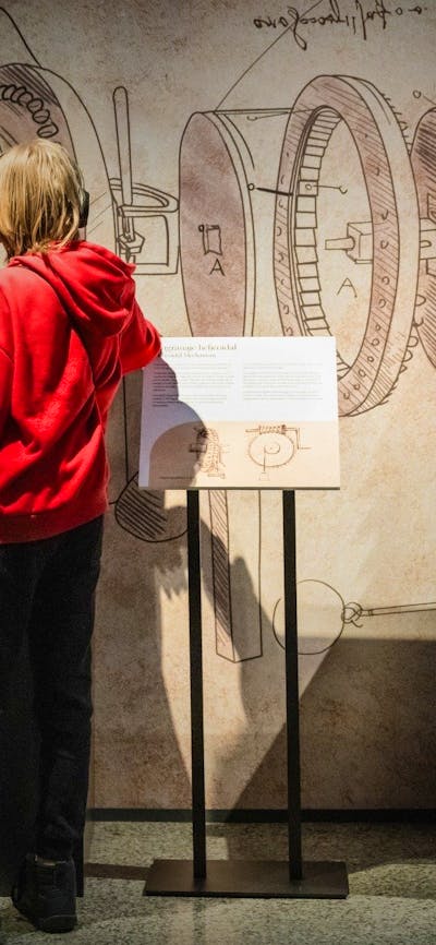 Visitor explores Leonardo da Vinci–inspired machines and sketches in an immersive exhibition.