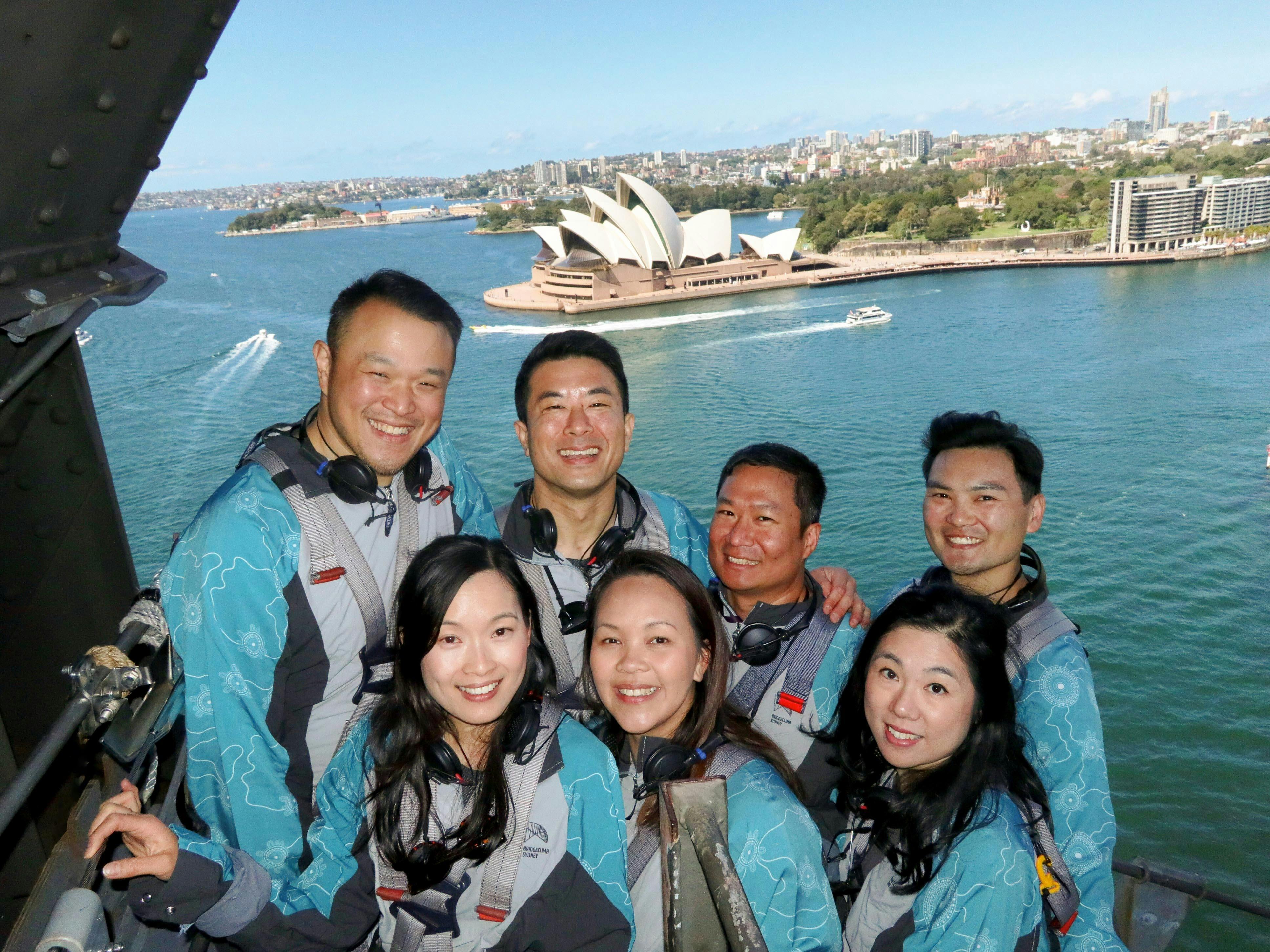 A group of people posing for  a photo on the Sydney Harbour Bridge with the Harbour behind
