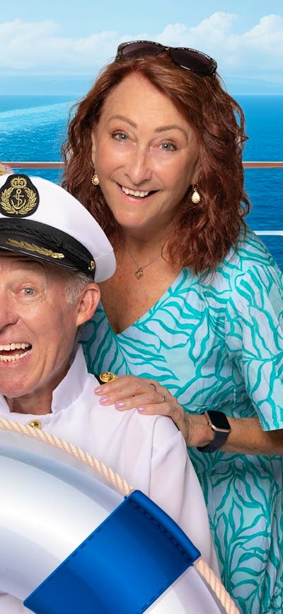 Four people standing on a boat with a life ring in front of them, smiling at the camera
