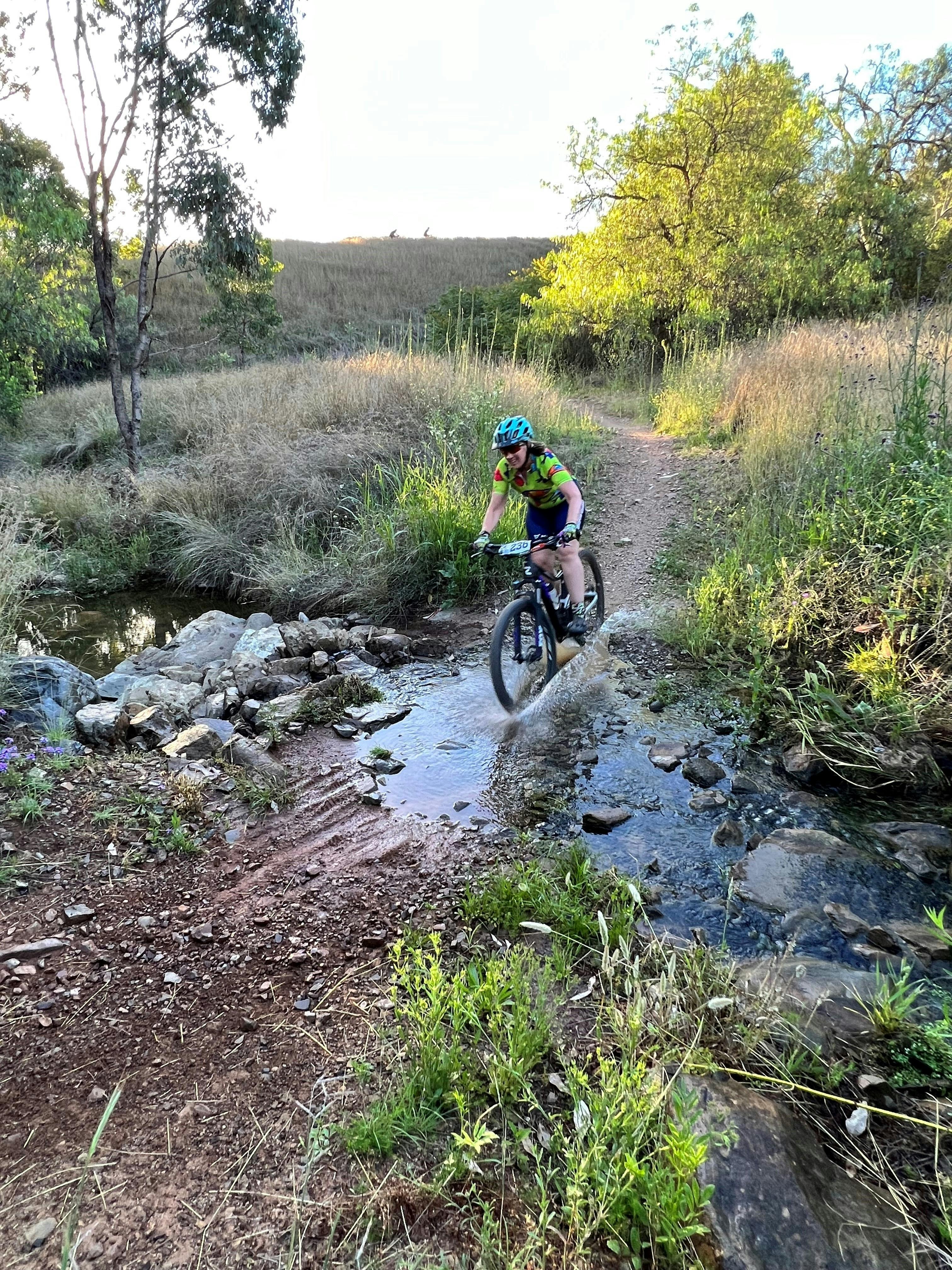 Photo of mountain bike rider crossing through a small river