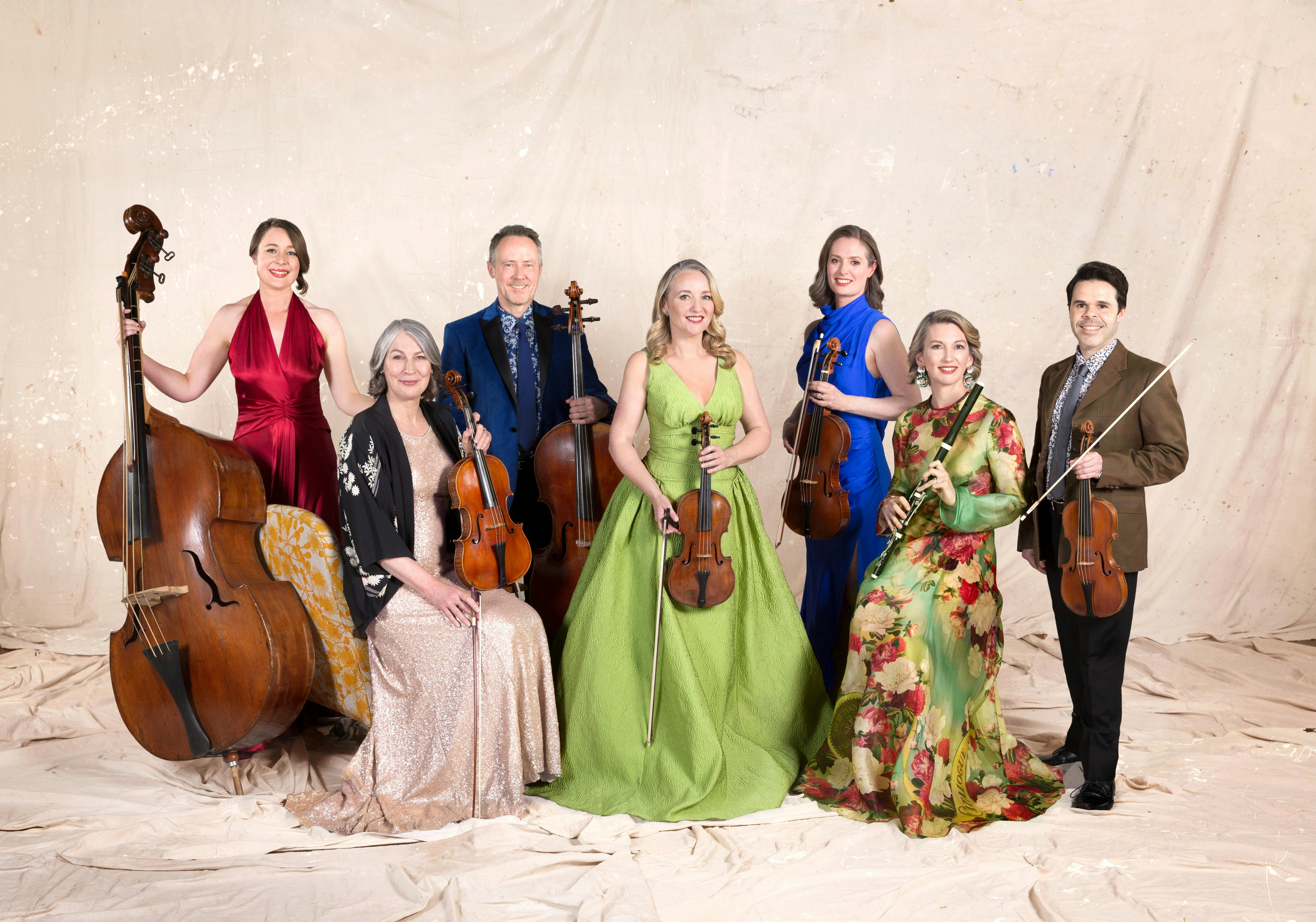 Seven classical musicians in elegant dress.