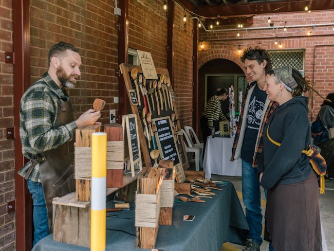 Artisan woodwork market stall, with the artist showing customers his art.