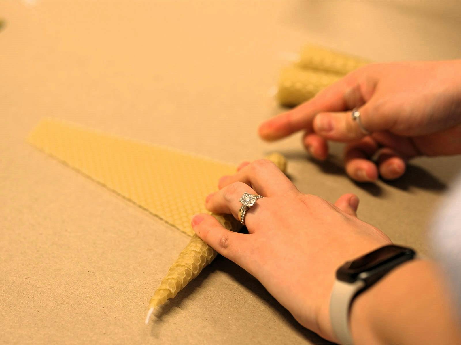 Hands rolling beeswax into a candle