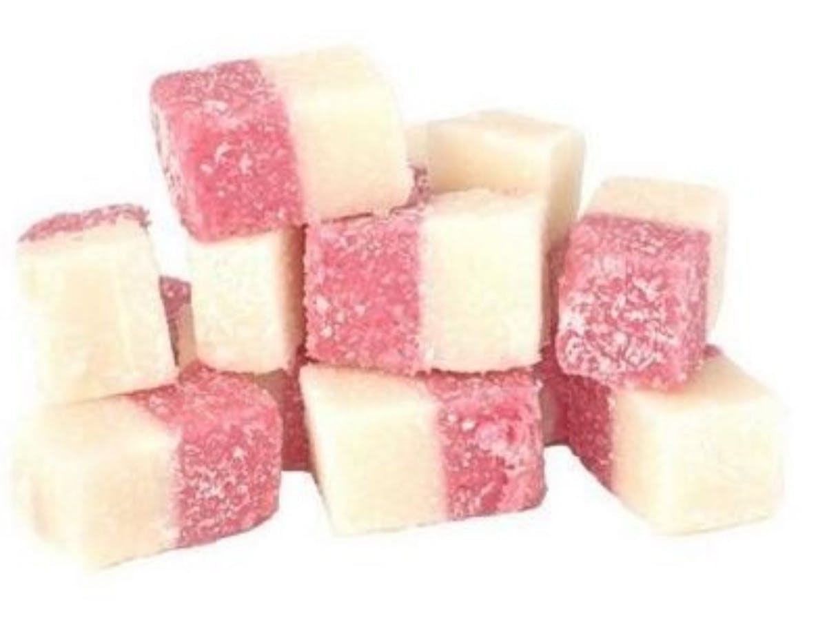 Pink and white cubes of creamy coconut ice dusted with coconut