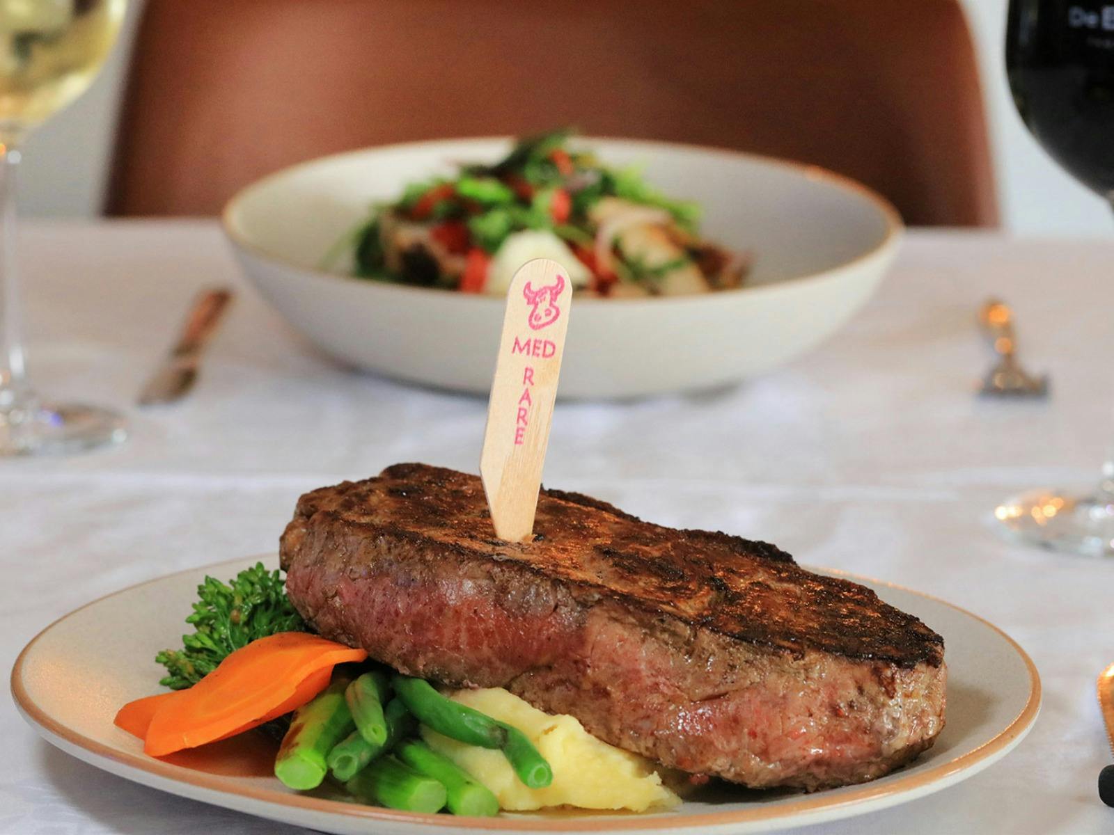 Medium rare steak with mash and vegetables