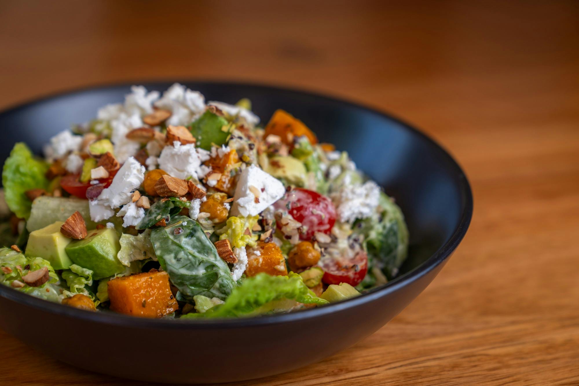 Salad with roasted pumpkin, avocado, crumbled feta, fluffy quinoa, greens & dressing plated