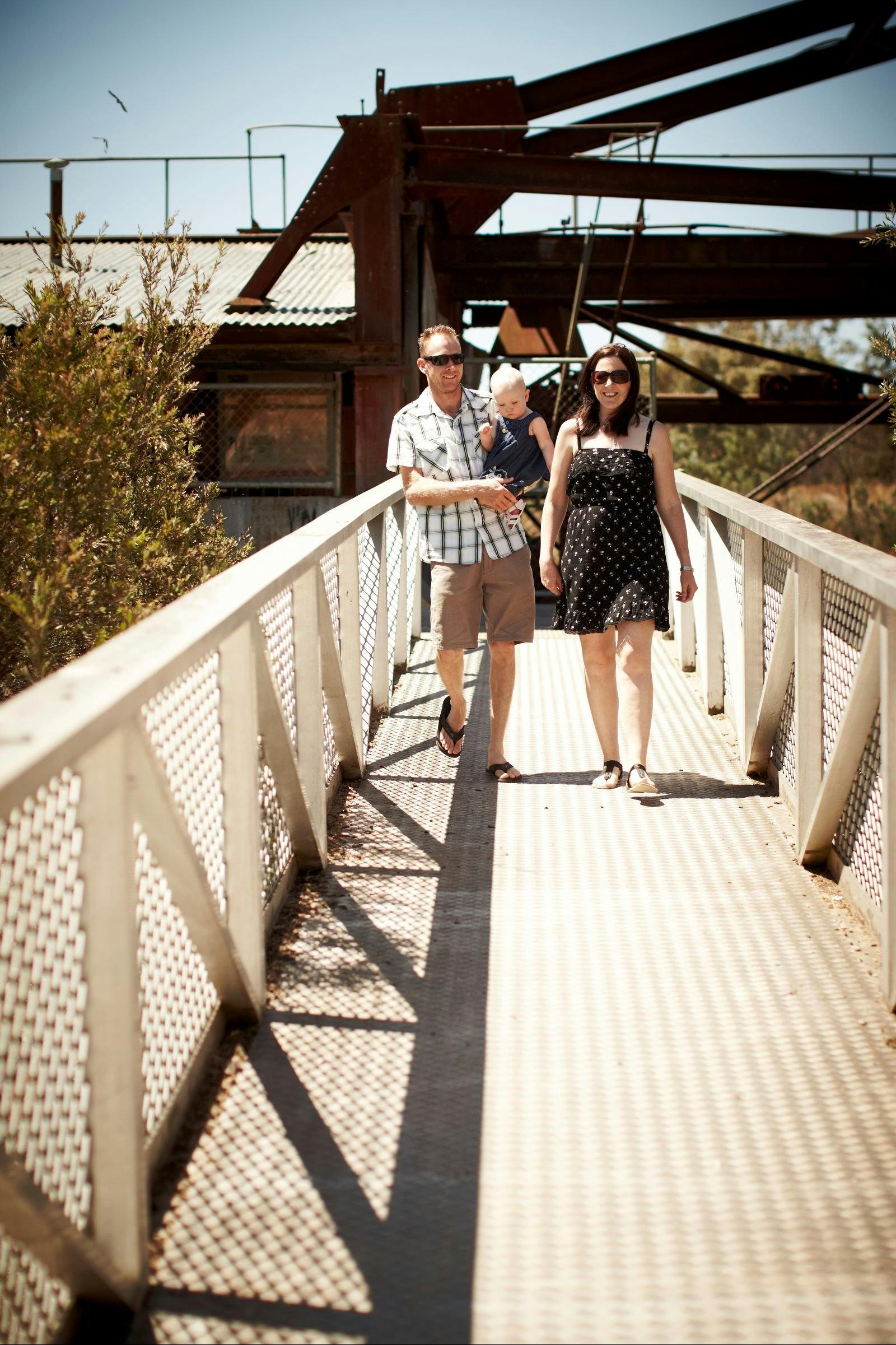 Family walking on a bridge with dredge in background