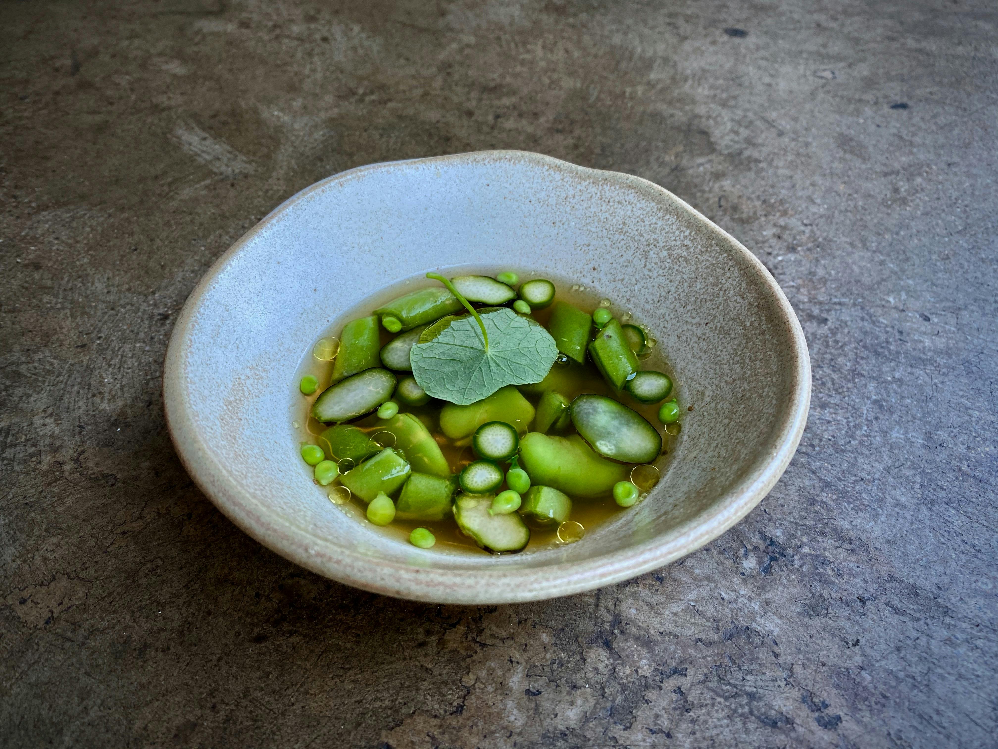 Broad beans, peas + nasturtium in a clear broth.