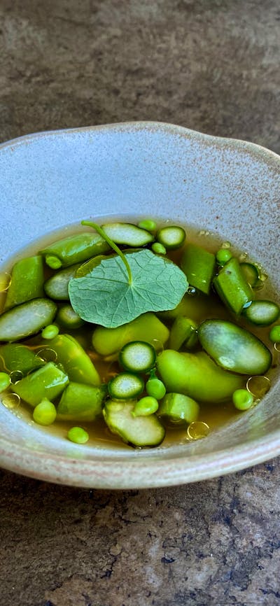 Broad beans, peas + nasturtium in a clear broth.