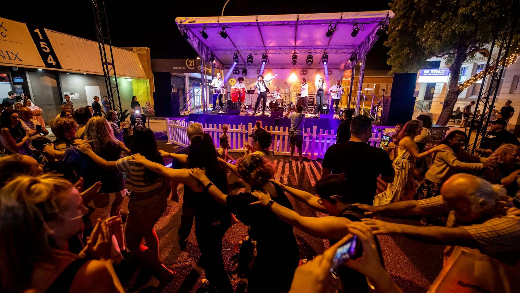 People dancing in front of a stage with their arms linked