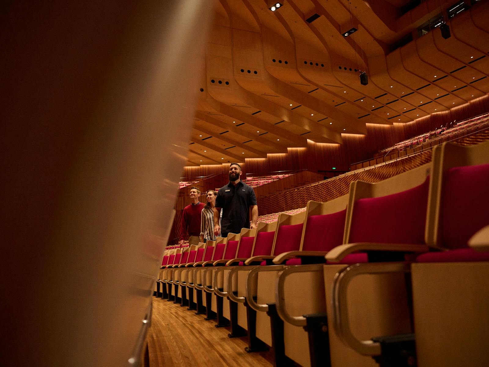 Tour guide leading a man and a woman through through the stalls in the Concert Hall