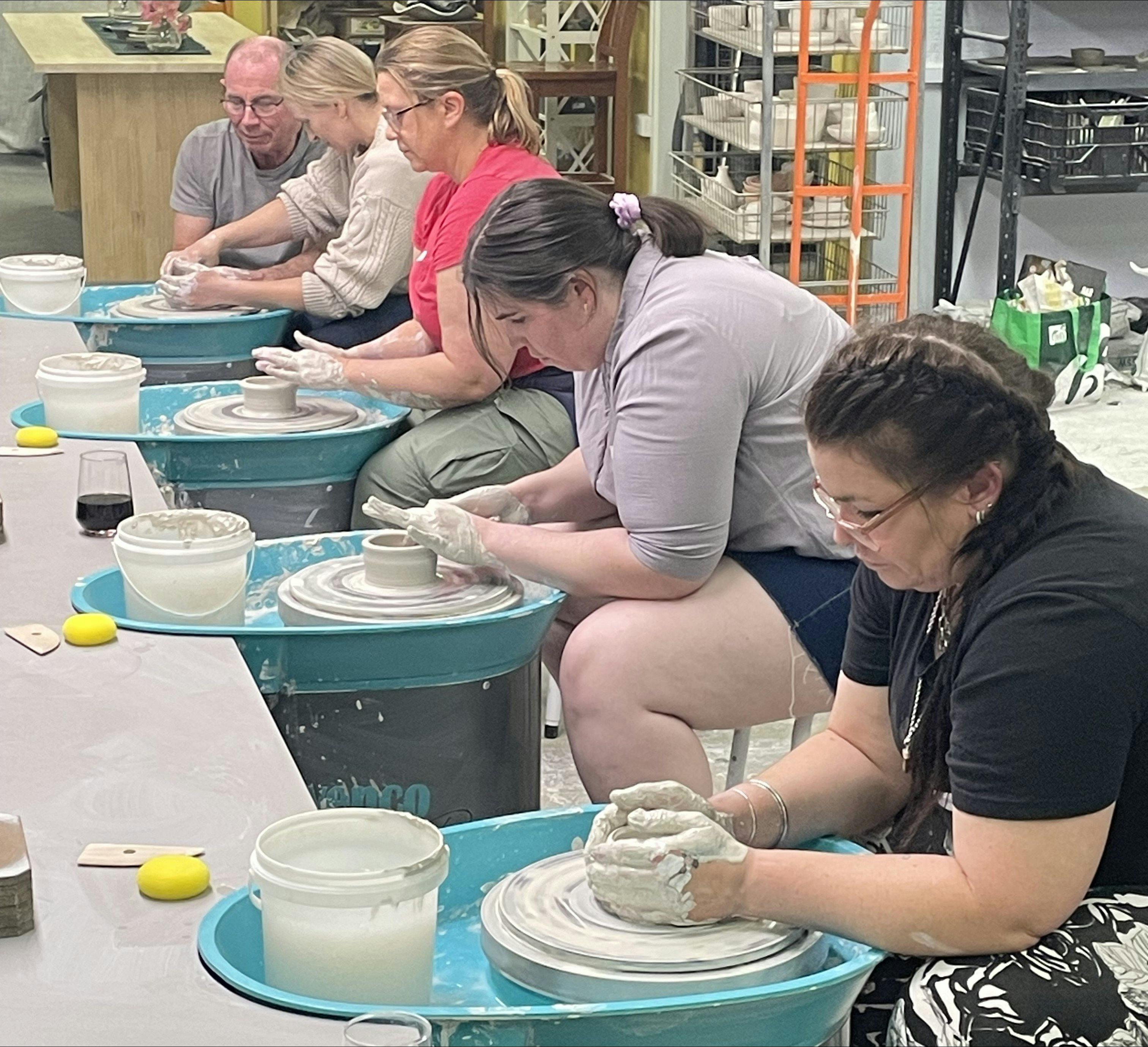 People wheel throwing in a pottery studio