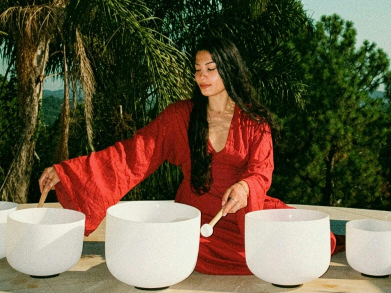 Woman seated playing crystal singing bowls