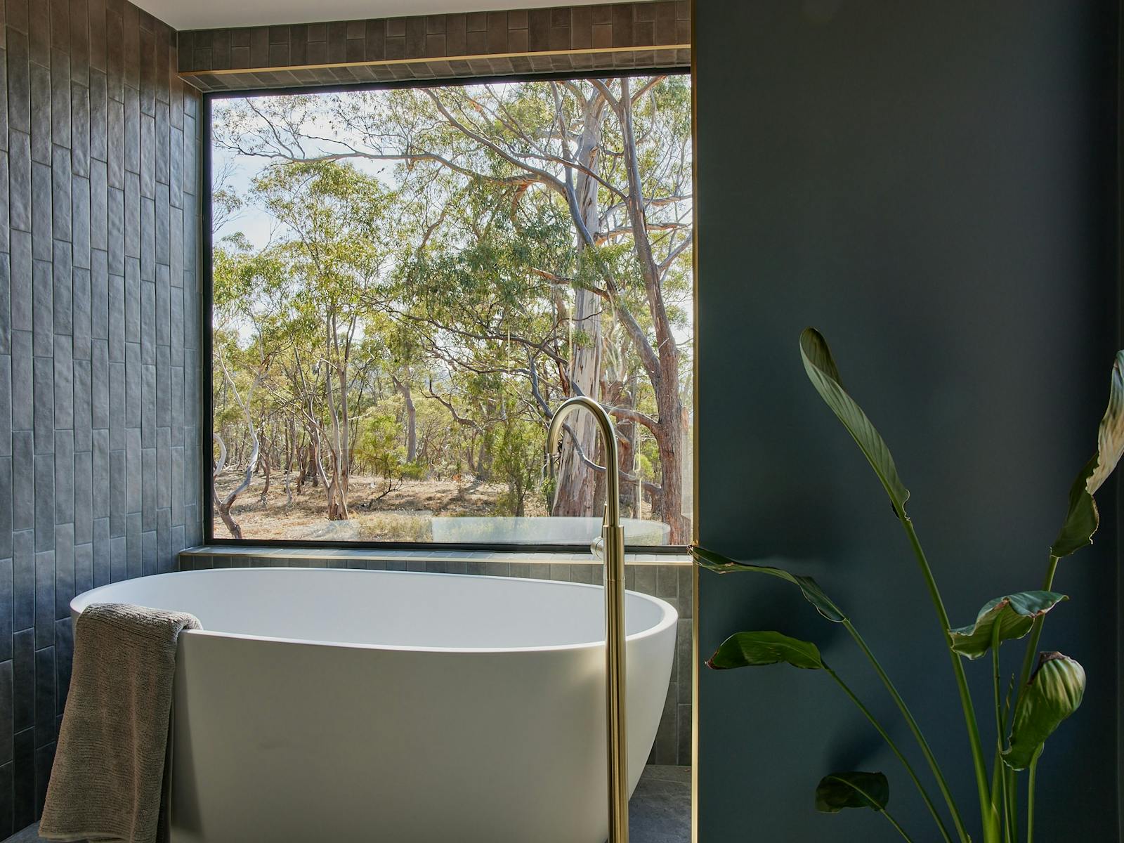 Bath in bathroom with large glass window and bush outlook